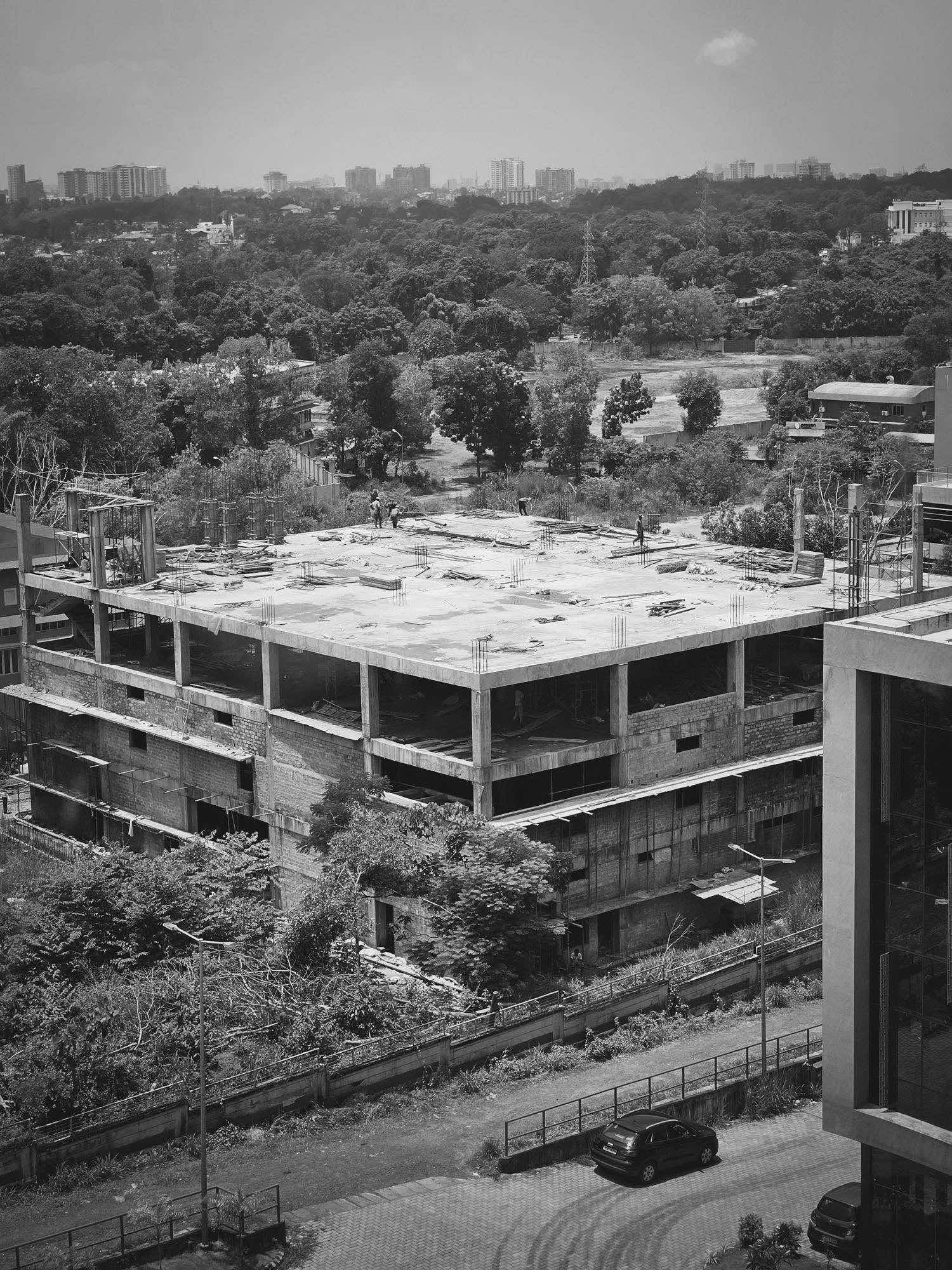 Vista aerea di un cantiere con edificio in costruzione e skyline sullo sfondo, bianco e nero